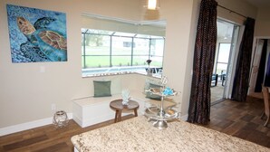 A kitchen with a granite countertop, a dining area with a bench, a window with a view of the outdoors, and a ceiling light fixture. - Lazy Gator (Rotonda West)