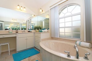 Une salle de bain moderne avec une grande baignoire, un meuble-lavabo avec un miroir et une fenêtre avec des rideaux.