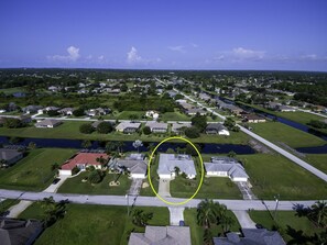 Vue aérienne d’un quartier résidentiel avec des maisons, des routes et une étendue d’eau.