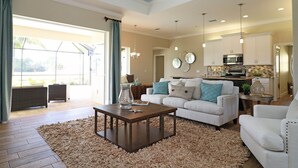 A spacious living room with a large window, a fireplace, and a kitchen in the background. - Blue Pearl (Rotonda West)