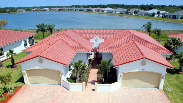 A two-story house with a red-tiled roof, two attached garages, and a paved driveway. - Happy Days at Alhambra (Port Charlotte)