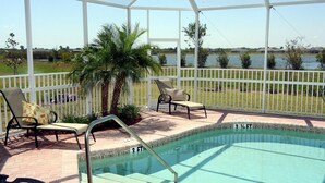 A covered outdoor swimming pool with lounge chairs and a palm tree. - Happy Days at Alhambra (Port Charlotte)