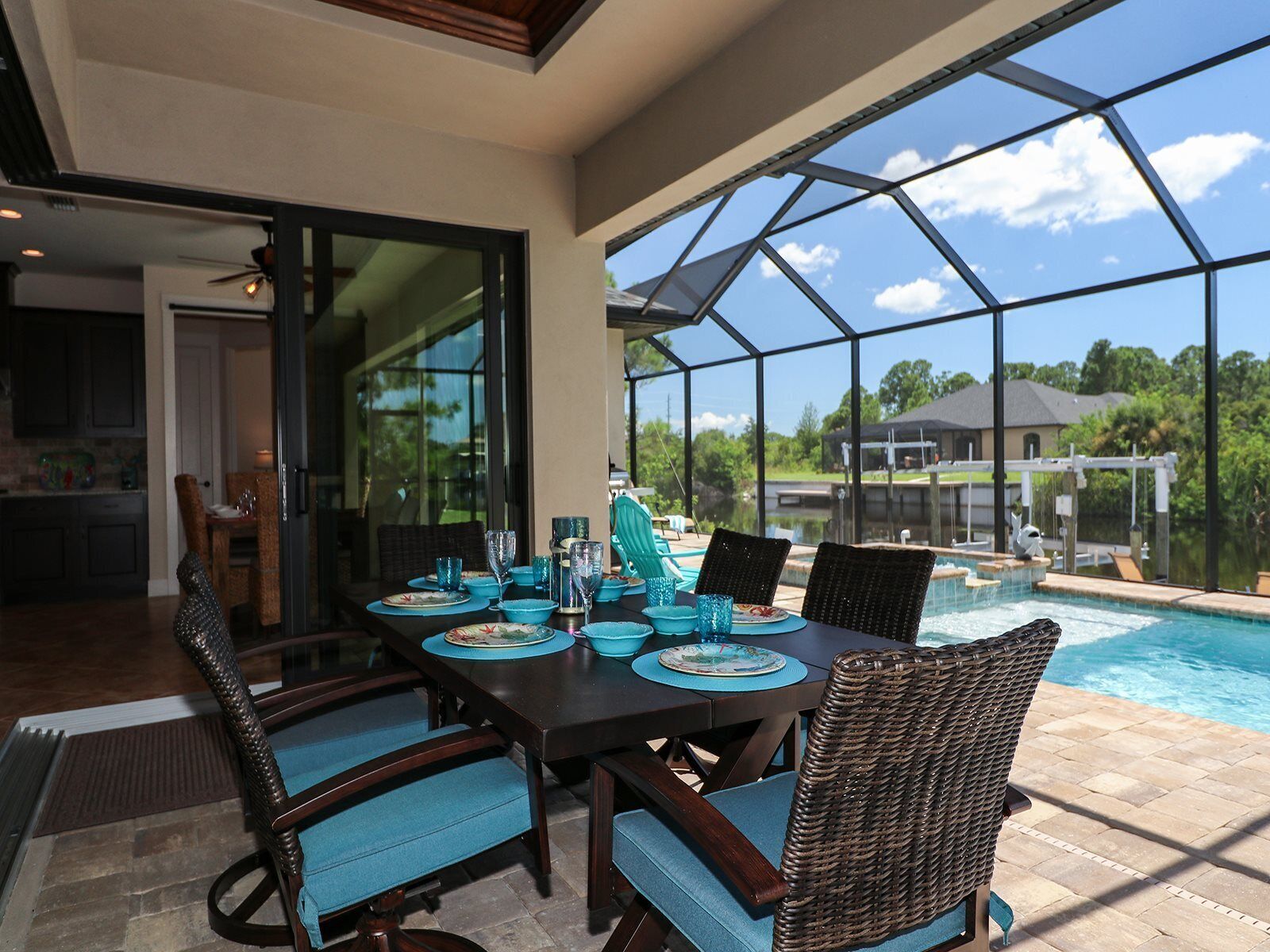 Uma área de refeições com uma mesa posta para quatro pessoas, com vista para uma piscina e um quintal.