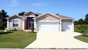 A single-story house with a garage, a front lawn, and a driveway. - Dolphin Cove (Port Charlotte)