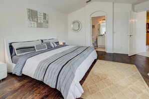 Un dormitorio con una cama grande, una mesita de noche, un espejo y una puerta que da a un baño.