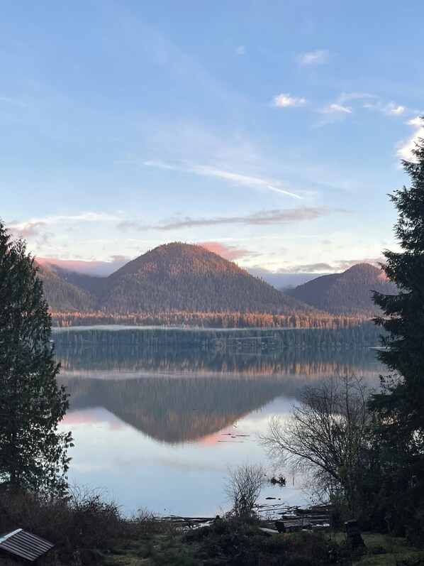 A serene lake with forested mountains in the background and a clear sky.
