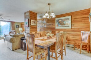 A dining area with a wooden table, chairs, and a chandelier. - Townhouse-style condo on golf course w/ open living room and balcony (Sugar Mountain)