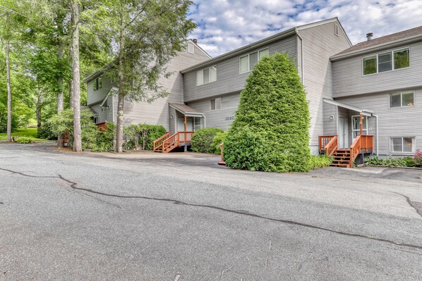 A residential building with a grey exterior, multiple windows, and a well-maintained lawn. - Townhouse-style condo on golf course w/ open living room and balcony (Sugar Mountain)