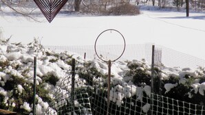 Ein herzförmiges Windspiel hängt drinnen, durch ein Fenster ist eine verschneite Landschaft zu sehen.