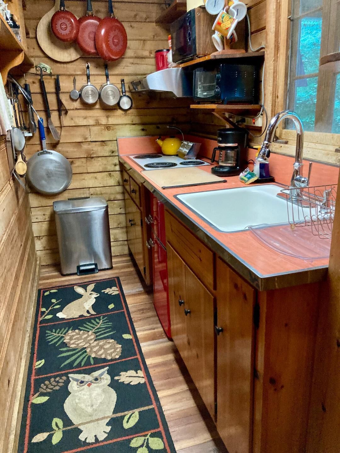 A compact kitchen with wooden cabinets, a sink, a stove, and various kitchen utensils.