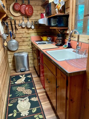 A compact kitchen with wooden cabinets, a sink, a stove, and various kitchen utensils.