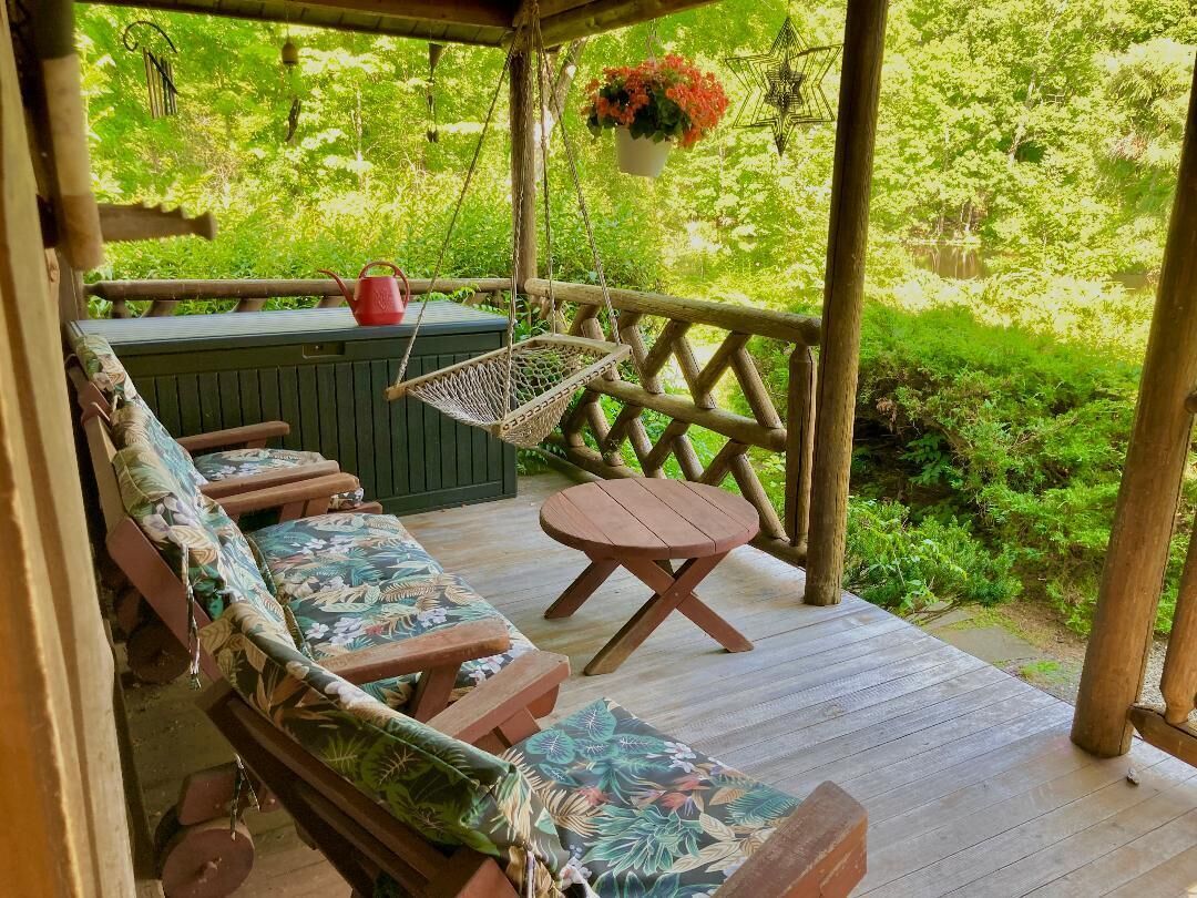 A wooden deck with a hammock, a bench, and a table.