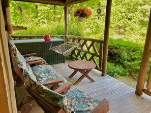 Een houten terras met een hangmat, een bank en een tafel.