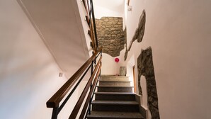 A staircase with a wooden handrail, stone walls, and a decorative element hanging from the ceiling. - Le Undici Rose Hotel (Viterbo)