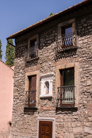 A stone building with two balconies, a wooden door, and a window with a white frame. - Le Undici Rose Hotel (Viterbo)