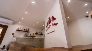 A reception area with a wooden reception desk, a wall-mounted sign for Le Undaria Rose, and shelves with bottles. - Le Undici Rose Hotel (Viterbo)