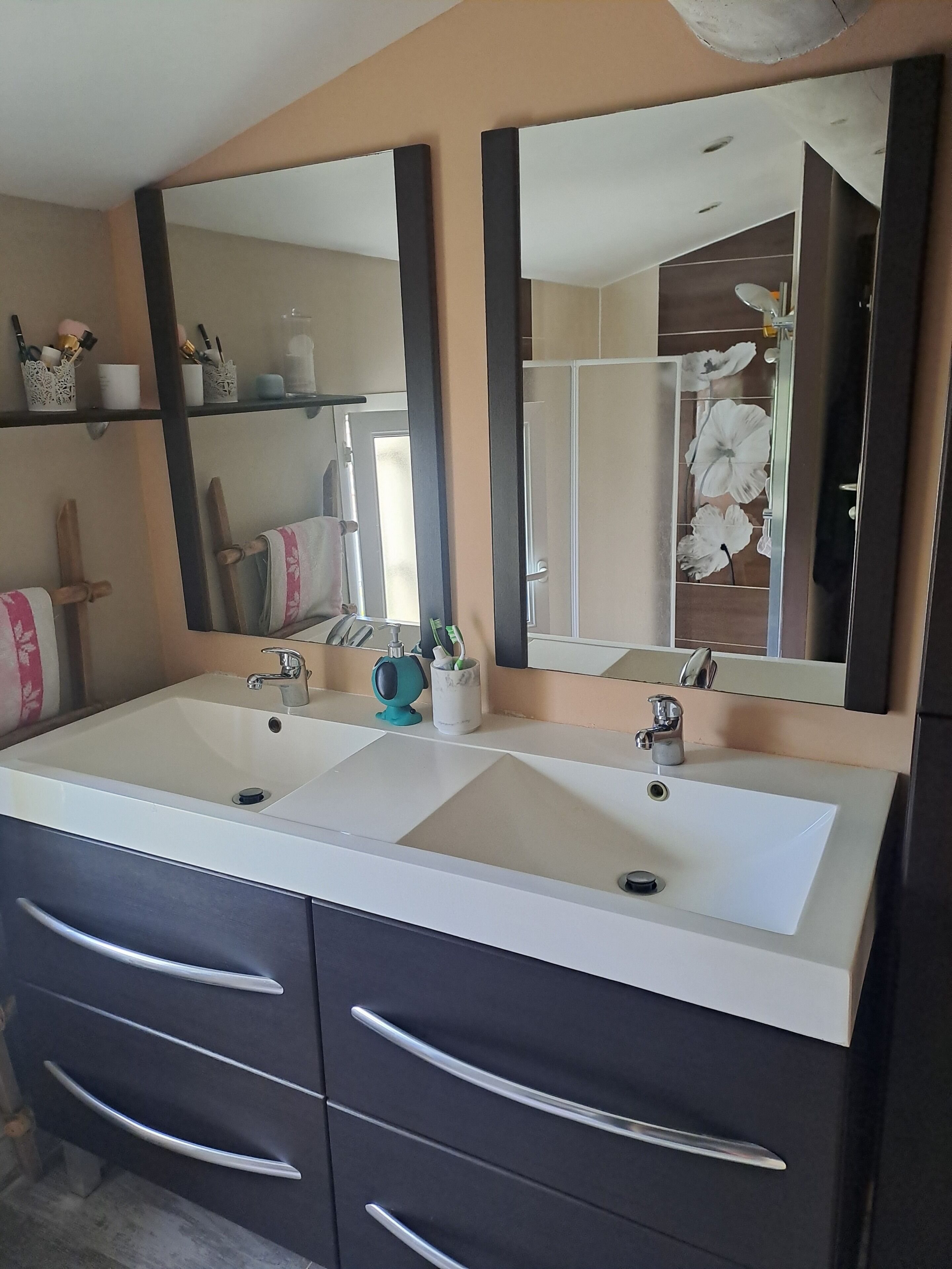 A bathroom with a double sink vanity, two mirrors, and a cabinet with drawers.