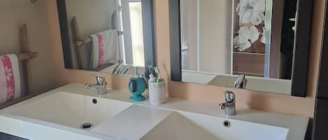 A bathroom with a double sink vanity, two mirrors, and a cabinet with drawers.