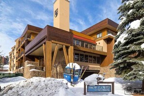 Un edificio moderno de varios pisos con un telesilla y un letrero que dice 'Snow Power Condominiums'.