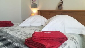 Een keurig opgemaakt bed met witte lakens en een rode handdoek ernaast.