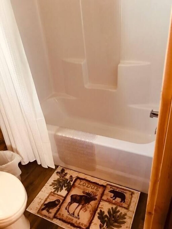 Un baño con bañera, inodoro y alfombra de estampado animal.