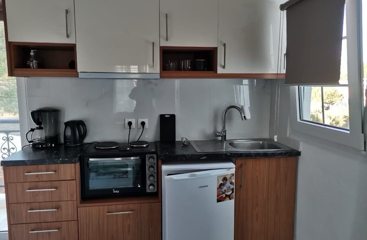 Uma cozinha compacta equipada com micro-ondas, cafeteira e frigorífico.