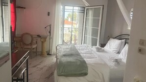 Un dormitorio con cama, escritorio, silla y ventana con cortinas.