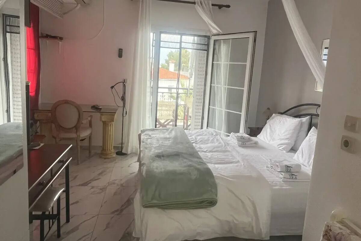 Une chambre à coucher avec un lit, un bureau, une chaise et une fenêtre avec des rideaux.
