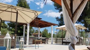 Un patio al aire libre con una pérgola, asientos y faroles.