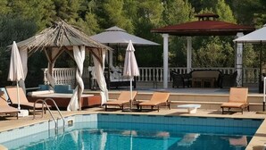 Una piscina con sillas de descanso y un pabellón.
