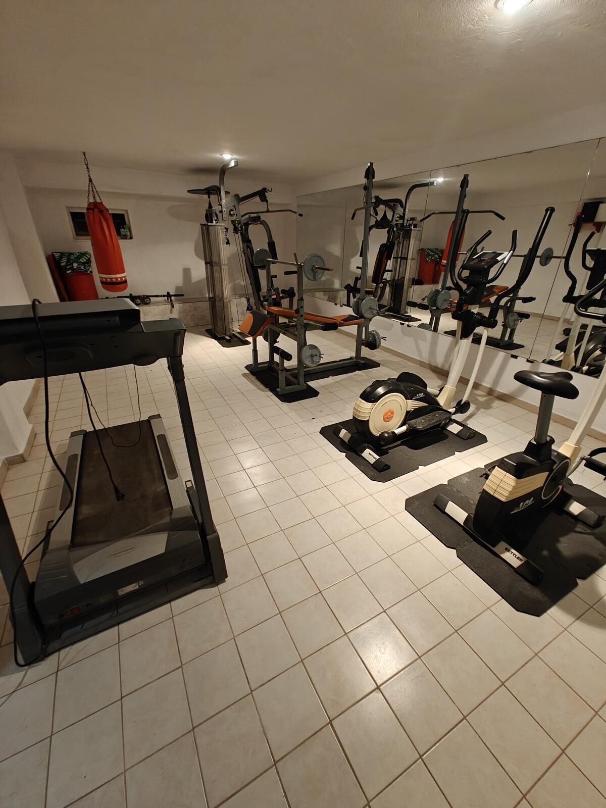 A gym with various exercise equipment, including treadmills, stationary bikes, and weight machines.