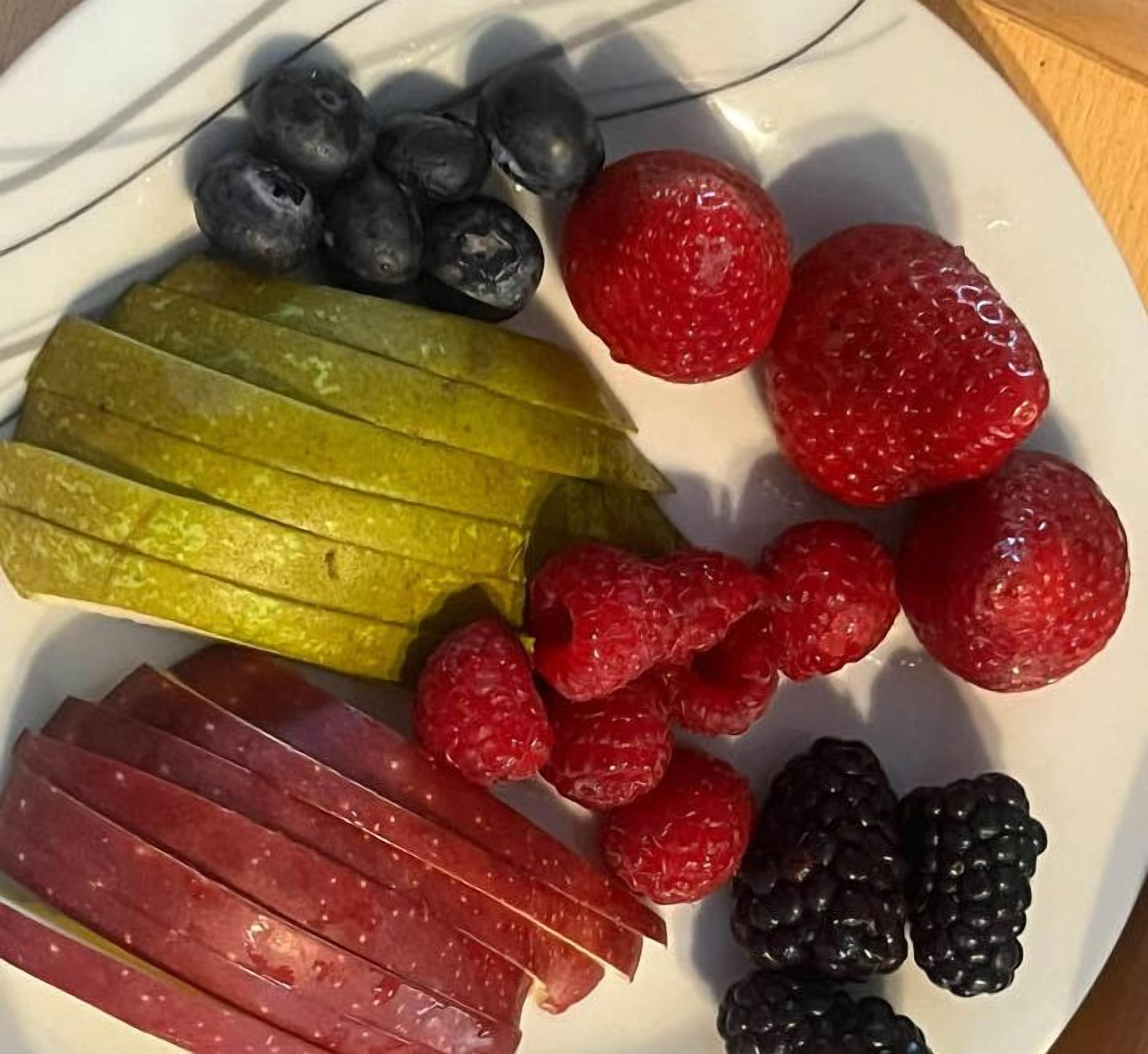 Ein Teller mit Gurkenscheiben, Himbeeren, Brombeeren und Blaubeeren.