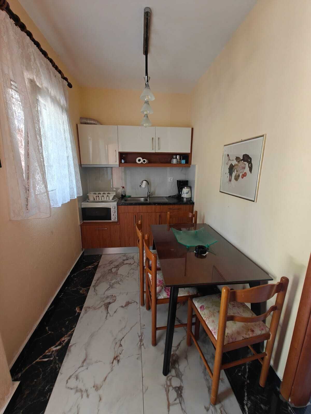 Una cuina compacta amb taula de menjador, cadires, una màquina de cafè i un llum penjant.