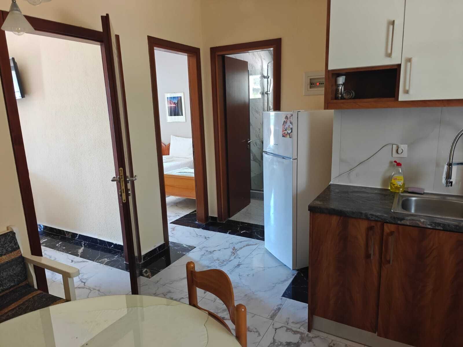 A kitchen with a refrigerator, a sink, and a dining area with a table and chairs.