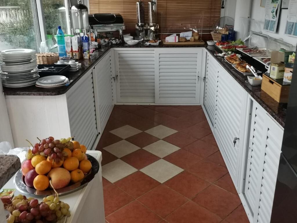 Une cuisine avec un carrelage à motifs, des placards blancs et un panier de fruits posé sur le comptoir.