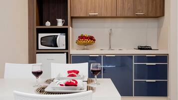 A modern kitchen with a microwave, a fruit bowl, and a dining table set with wine glasses and a red napkin.