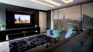 Een moderne woonkamer met een grote televisie, een bank en uitzicht op de stad.