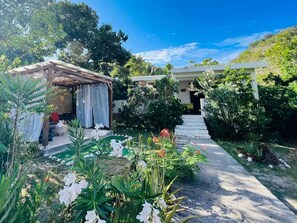 A garden with a pathway leading to a building with a covered entrance. - relaxing atmosphere, isolated at the foot of the mountain (Le bourg)