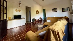 Un soggiorno con divano, televisore, un piccolo tavolino e un elemento decorativo a parete.