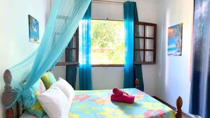 Un letto con una coperta a fiori, un paio di pantofole rosa e un baldacchino blu.