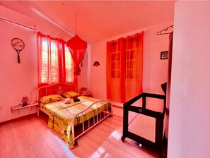 A bedroom with a bed, a nightstand, a hanging red canopy, and a crib. - relaxing atmosphere, isolated at the foot of the mountain (Le bourg)