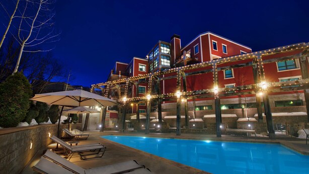 Ein Hotel mit Swimmingpool, Liegestühlen und einer überdachten Sitzgelegenheit.