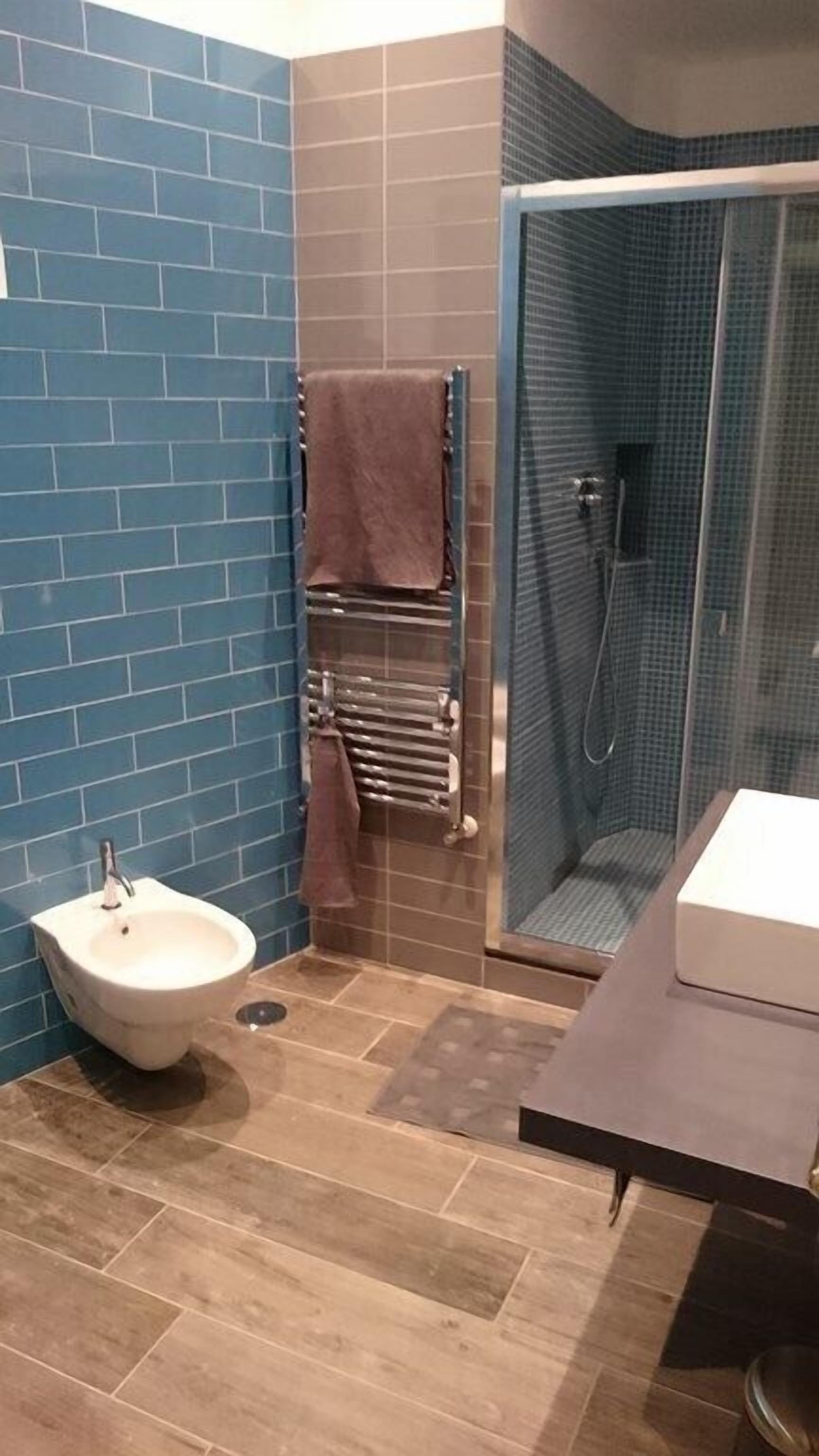 Un baño con bidé, cabina de ducha de vidrio y un perchero para toallas.