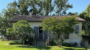 A two-story house with a tiled roof, a front porch, and a well-maintained lawn. - for rent Aignan Gers (French Tuscan) (Aignan)