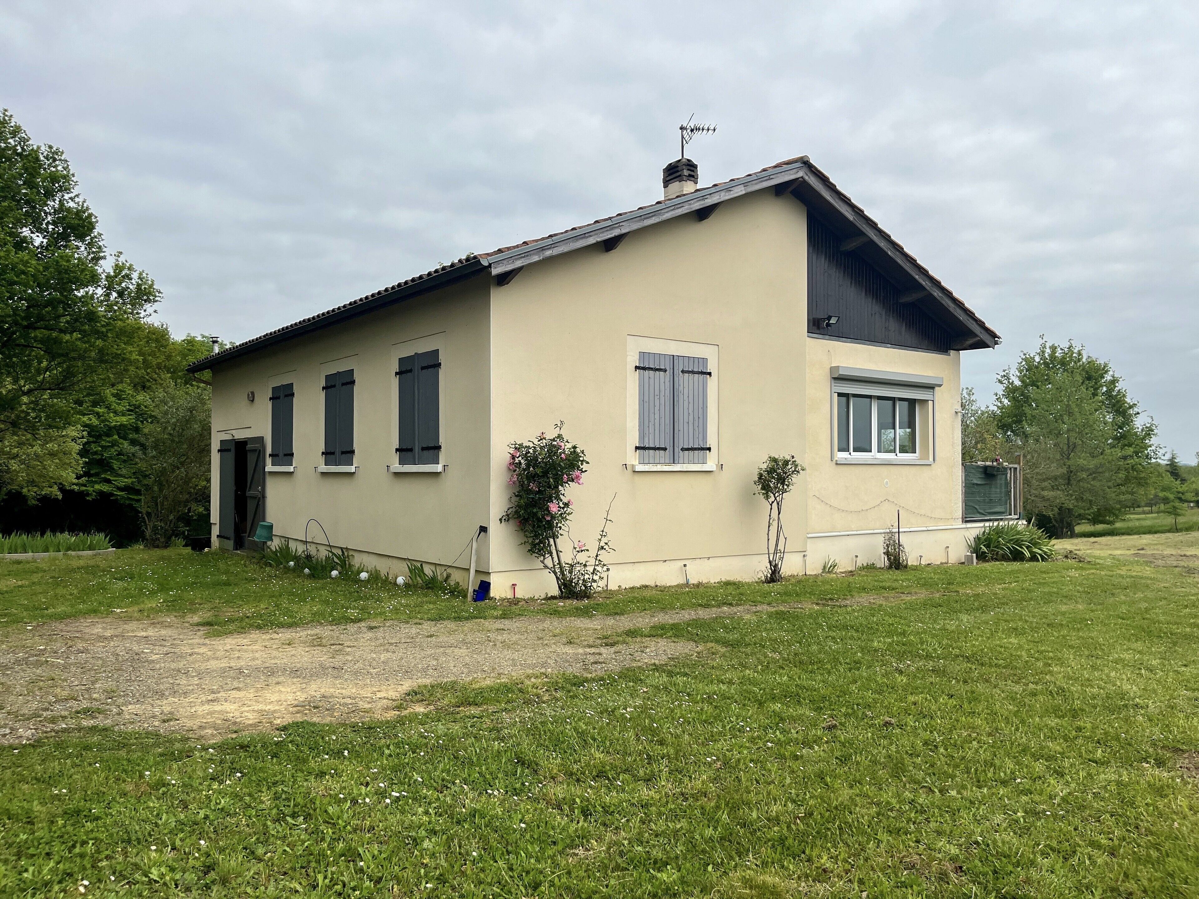 Une maison de plain-pied avec un toit en pente, une cheminée et un petit porche.