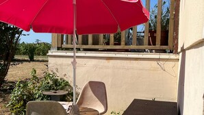 An outdoor seating area with a red umbrella, two chairs, and a small table. - for rent Aignan Gers (French Tuscan) (Aignan)