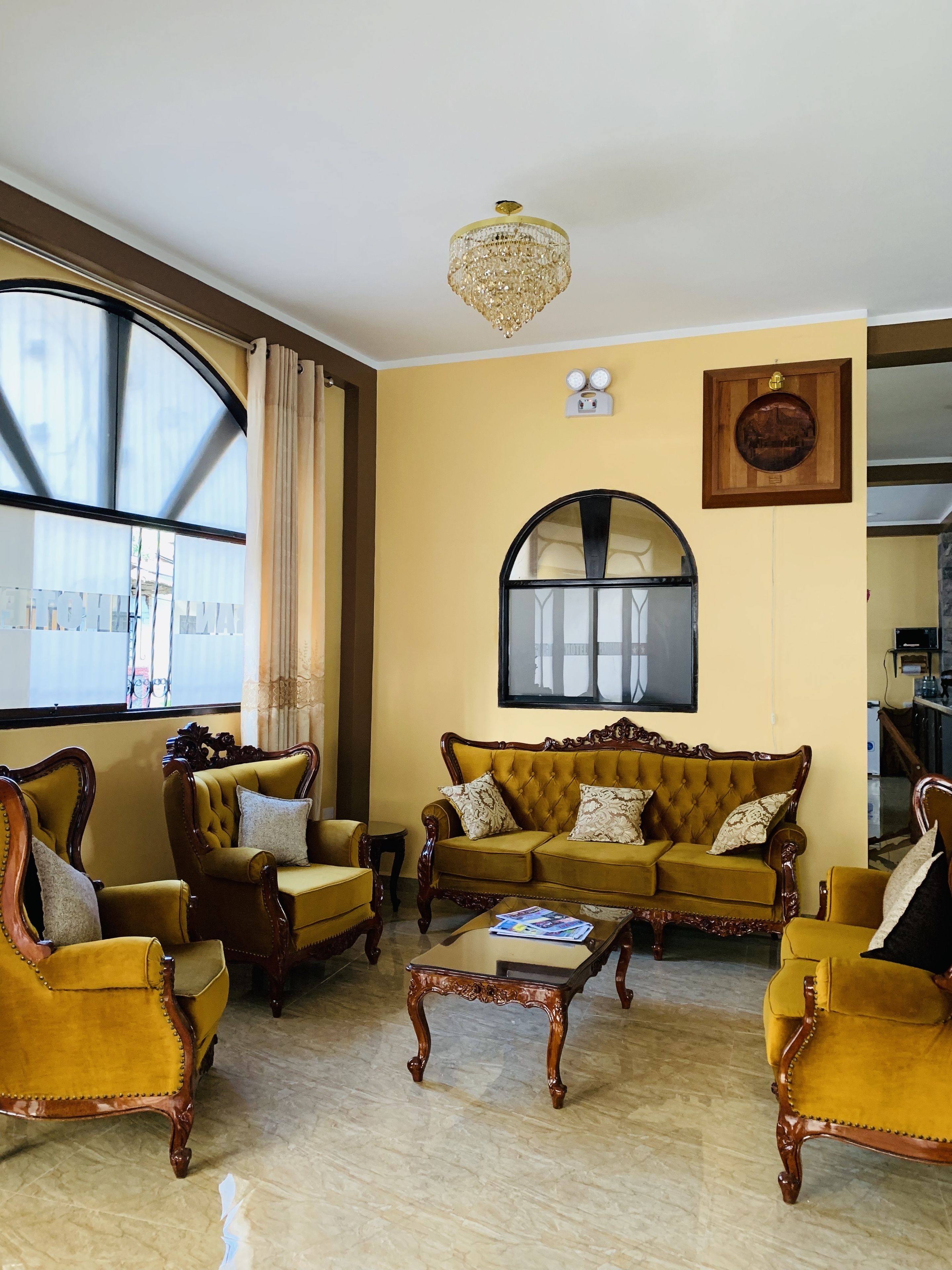 A living room with a yellow sofa, two armchairs, a coffee table, and a chandelier.