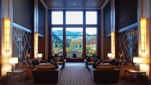 Eine geräumige Lobby mit großem Fenster und Blick auf die Berge, ausgestattet mit Sofas und Tischen sowie dekorativen Wandpaneelen.