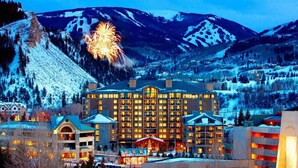 Ein Hotel mit mehreren Etagen und einem zentralen Atrium, umgeben von schneebedeckten Bergen und einem Skigebiet.