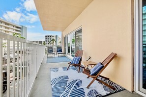 A balcony with two lounge chairs, a patterned rug, and a view of the cityscape.